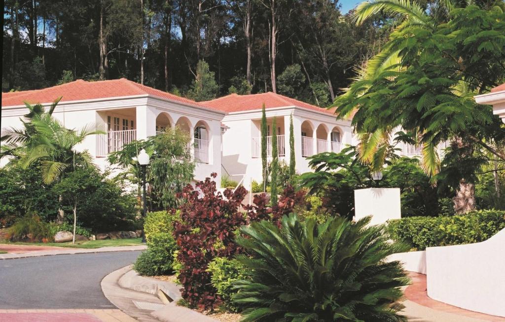 une maison blanche avec des arbres et des plantes devant elle dans l'établissement Royal Woods Resort, à Gold Coast