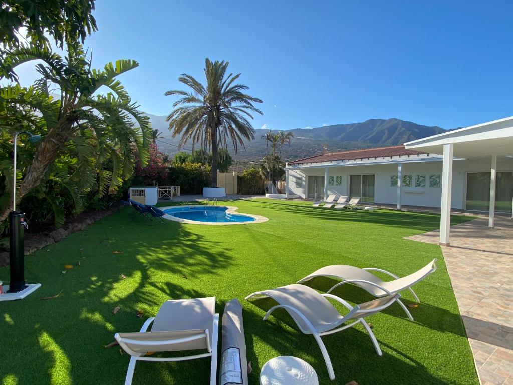 a yard with lawn chairs and a swimming pool at Arafo Sunset Villa in Arafo