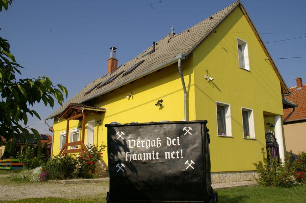 una casa amarilla con un cartel delante en Woldo Vendégház, en Töltéstava
