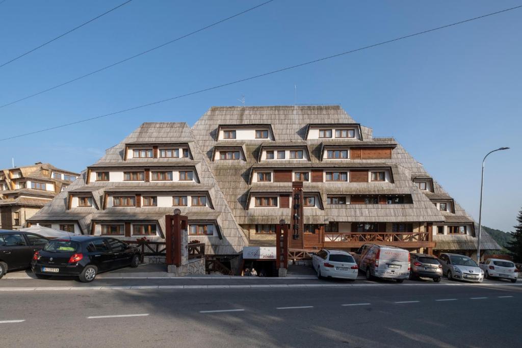 a large building with cars parked in a parking lot at Mila apartmani Kopaonik in Kopaonik