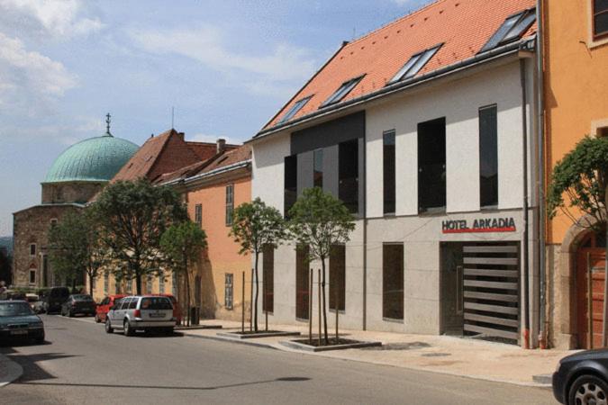 una calle de la ciudad con un edificio abovedado en Hotel Arkadia, en Pécs