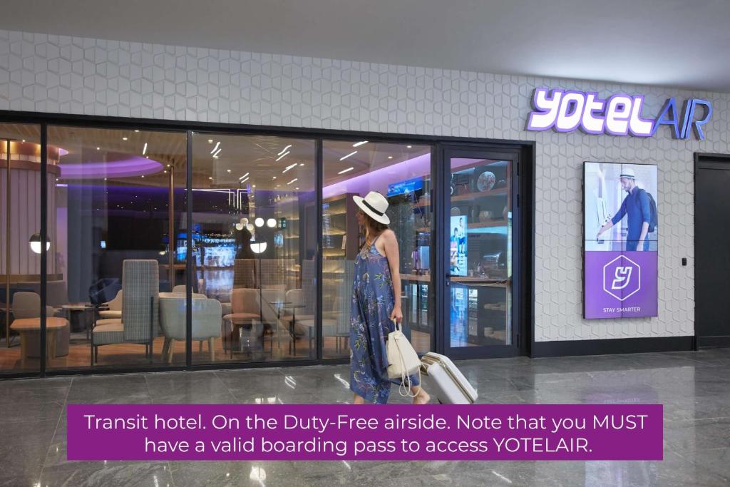 a woman is walking in front of a store at YOTELAIR Istanbul Airport, Duty free - International Transit area in Istanbul