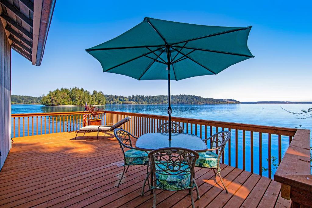 a table and chairs on a deck with an umbrella at Captain's Quarter in Johnson Landing