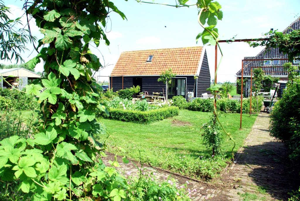 a garden with a house in the background at Bed In Waterland in Broek in Waterland