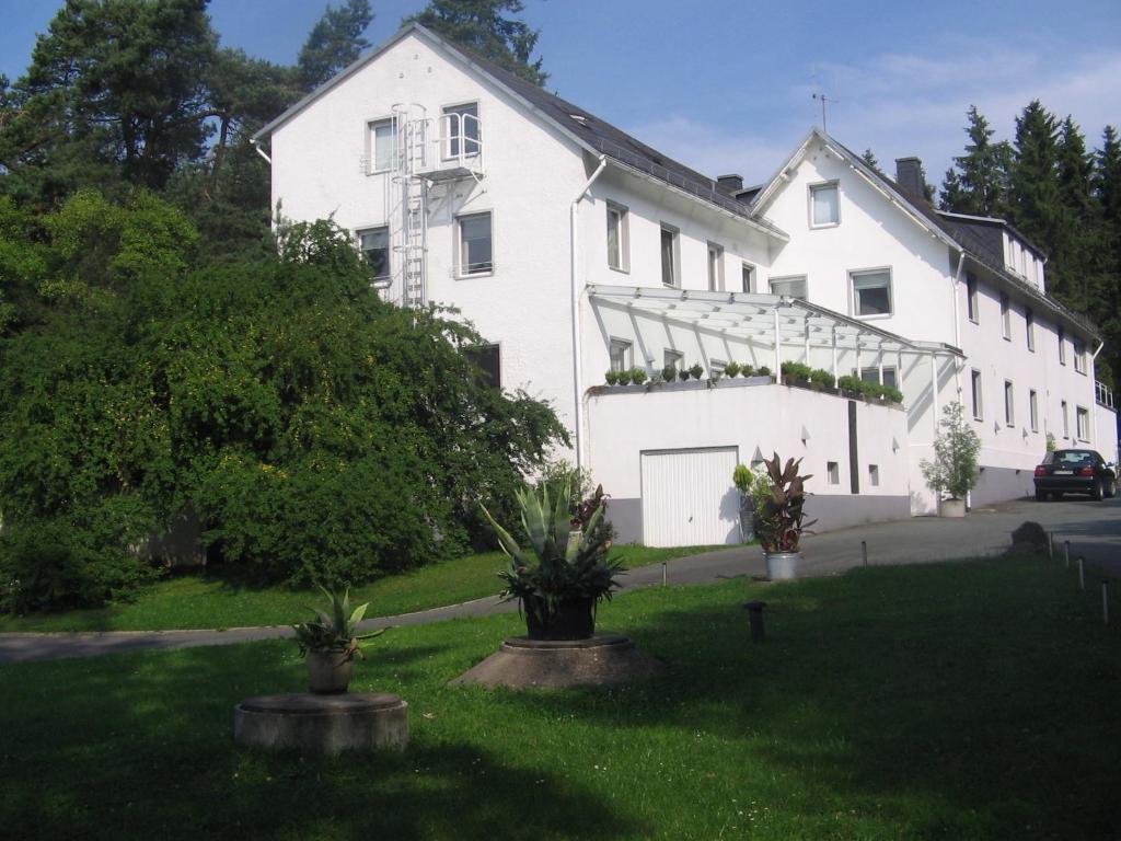 a large white house with plants in the yard at Hotel Ambiente in Hof