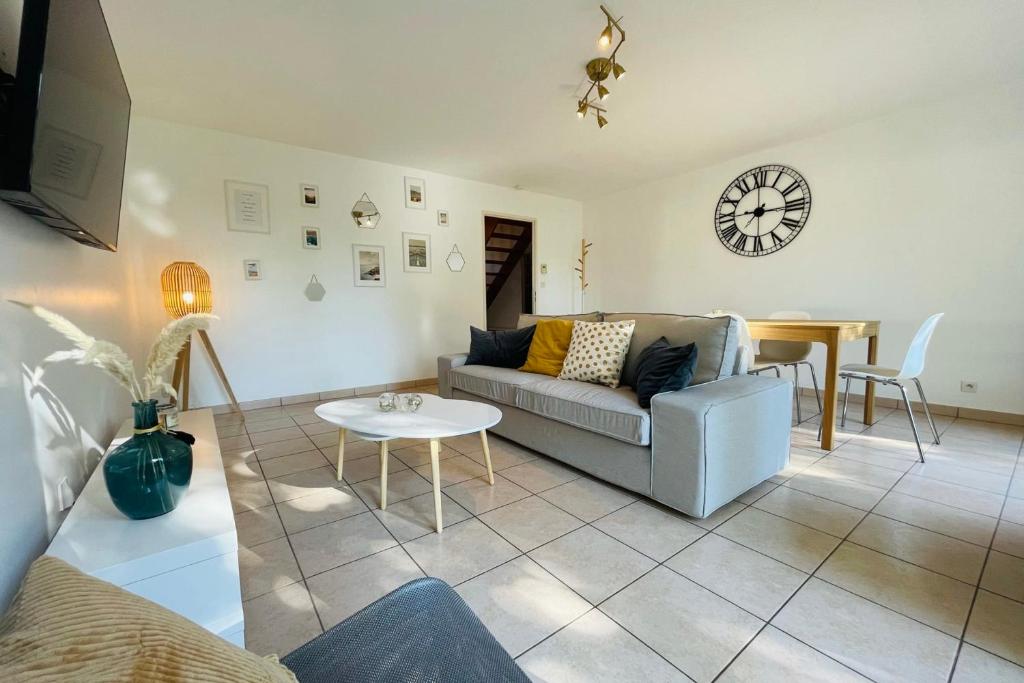 uma sala de estar com um sofá, uma mesa e um relógio em Maison rénovée dans quartier résidentiel aux portes de Tours em Véretz