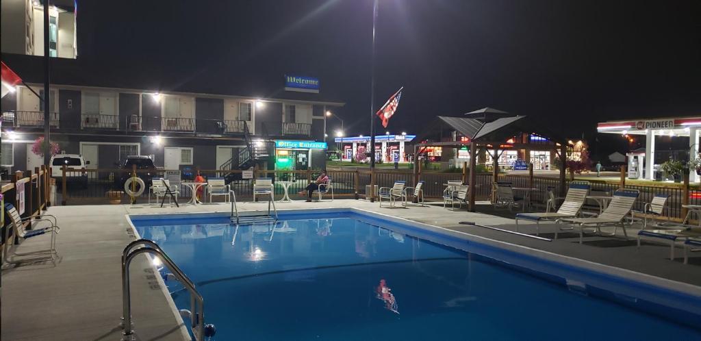 a swimming pool with chairs and a hotel at night at Niagara Falls Courtside Inn in Niagara Falls