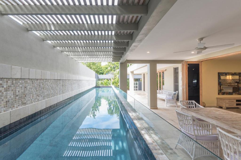 una piscina coperta con sedie e una piscina di Beachside Villa with Private lap pool a Port Douglas