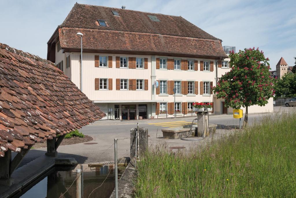un grand bâtiment blanc avec un toit marron dans l'établissement Avenches Youth Hostel, à Avenches