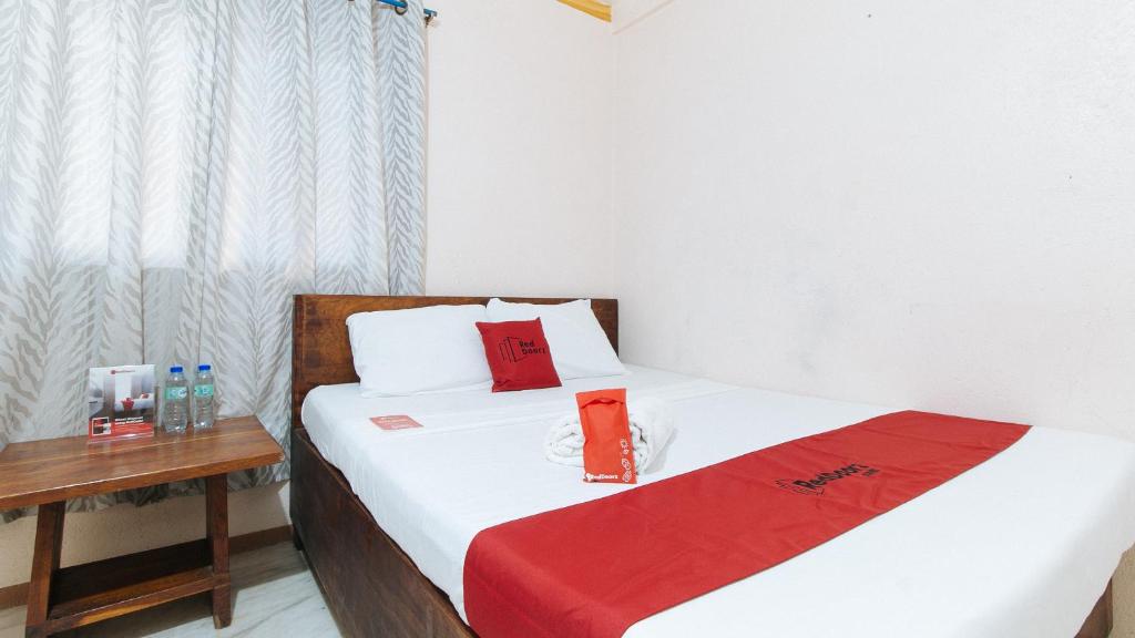 1 Schlafzimmer mit 2 Betten mit roten Kissen und einem Tisch in der Unterkunft RedDoorz Hostel @Megans Paradisio Beach Resort in Zambales