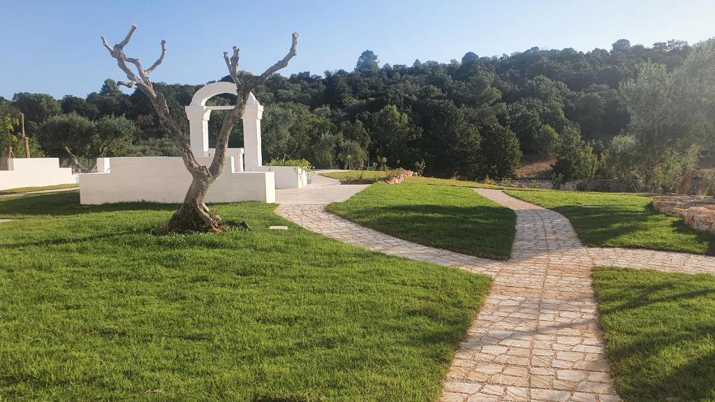 un chemin en pierre menant à un monument avec un arbre dans l'établissement Tenuta Marinelli, à Cisternino