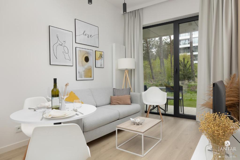 a white living room with a white couch and a table at Shellter Apartments 117 Ł - by Jantar Apartamenty in Rogowo