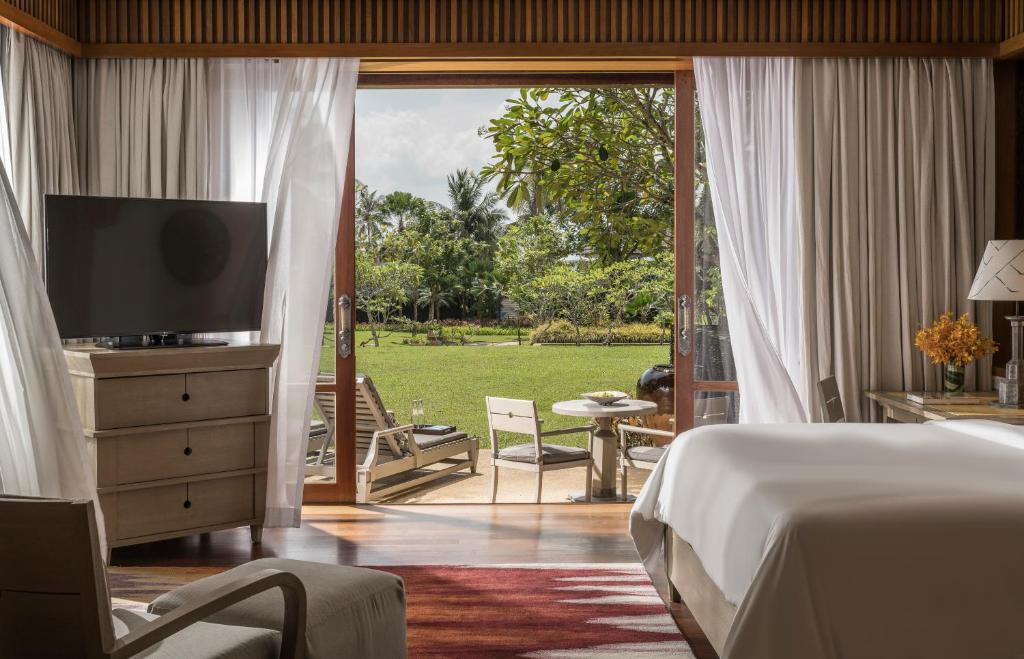 a bedroom with a bed and a television and a patio at Four Seasons Resort Langkawi in Tanjung Rhu