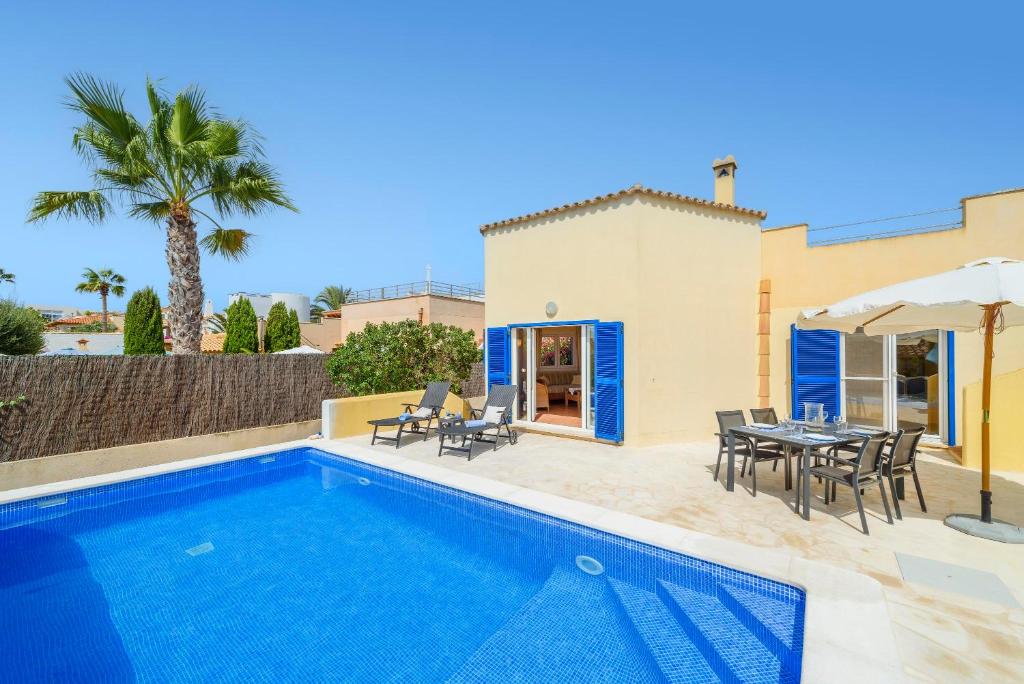 a villa with a swimming pool and a table and chairs at Casa Folara in Cala Llombards