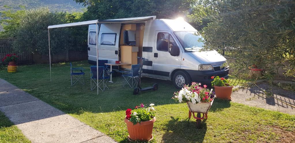 ein weißer Van auf einem Hof mit Pflanzen geparkt in der Unterkunft Camper van Montenegro in Podgorica