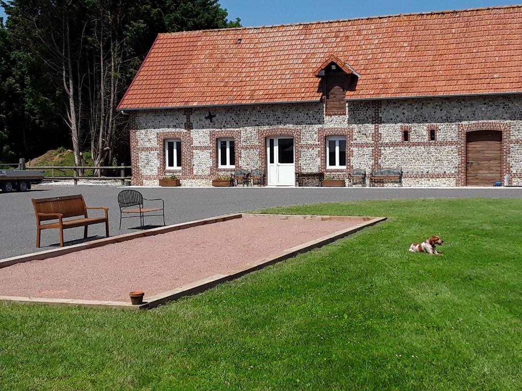 Thiergevilleにあるla grange aux hortensiasの建物前の芝生に寝た犬