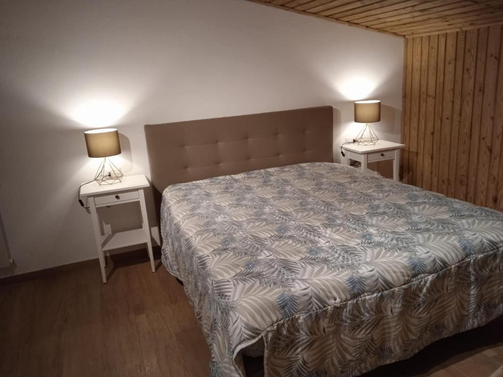 sypialnia z łóżkiem i dwoma stołami z lampkami w obiekcie La Mansarda w mieście Lozzo Cadore