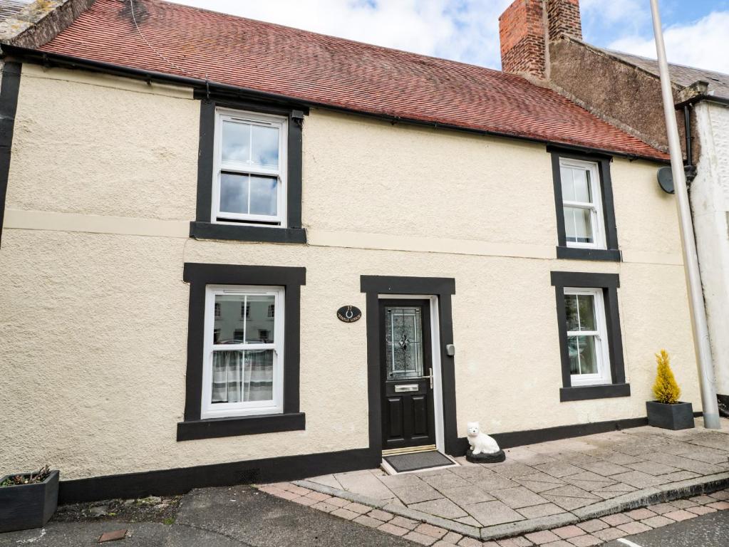 a house with a cat sitting outside of it at Stable Lodge in Coldstream