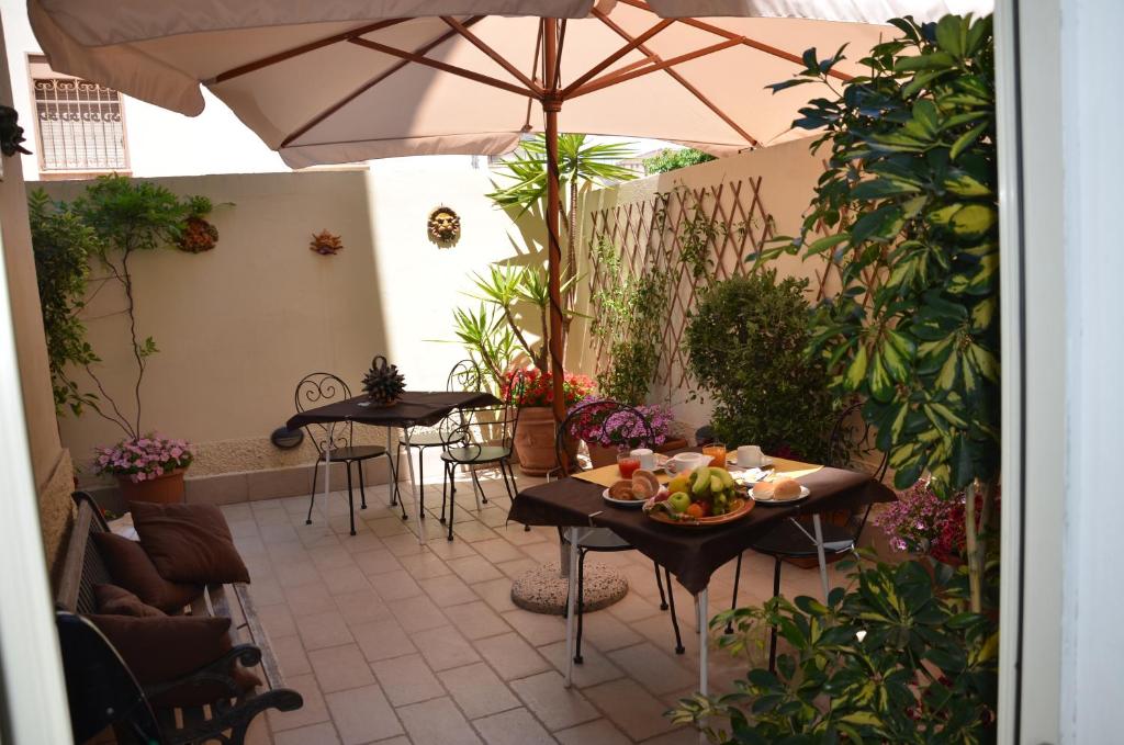 un patio con mesas, sillas y una sombrilla en Possidonea 28, en Reggio Calabria