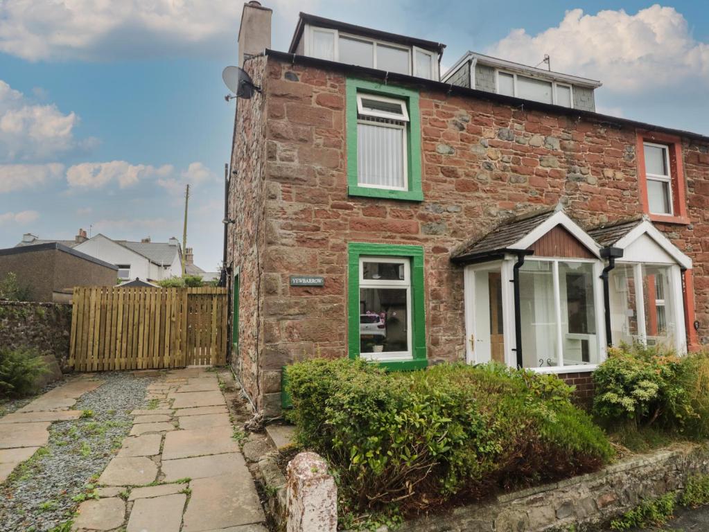 a brick house with green windows and a fence at Yewbarrow in Seascale