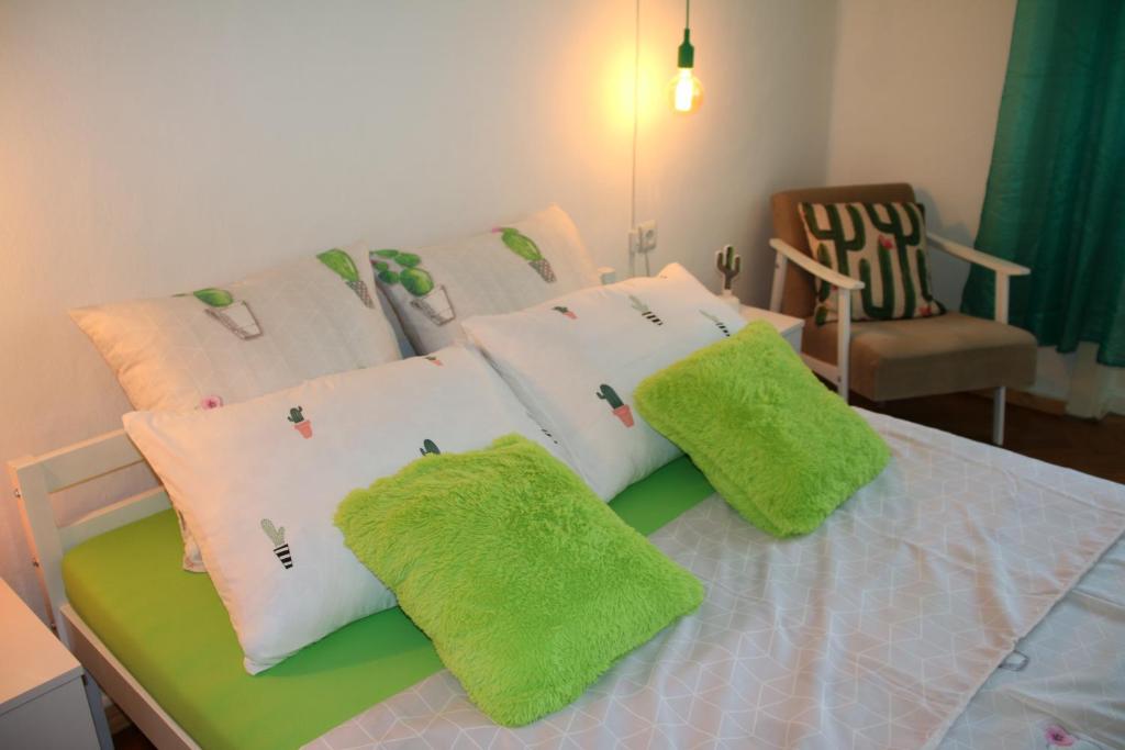 a bed with four pillows on it with a chair at Green Cactus Rooms - unique and cozy house in Senta