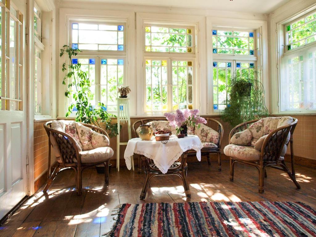 a dining room with a table and chairs and windows at Ezera Maja in Liepāja