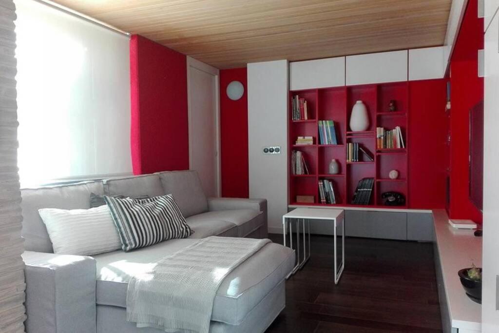 a living room with a couch and a red wall at Cozy designer apart / Acogedor apartamento de diseño ● WiFi - Jacuzzi - A/C SteamSauna in Madrid