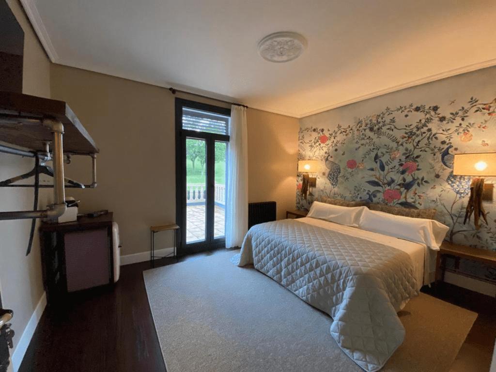 1 dormitorio con 1 cama con pared de flores en Alojamiento Casa Indiana La Escondida, en Muskiz