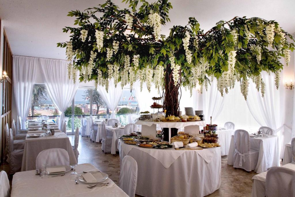 una stanza con tavoli bianchi e un albero di Hotel Heaven a Rimini