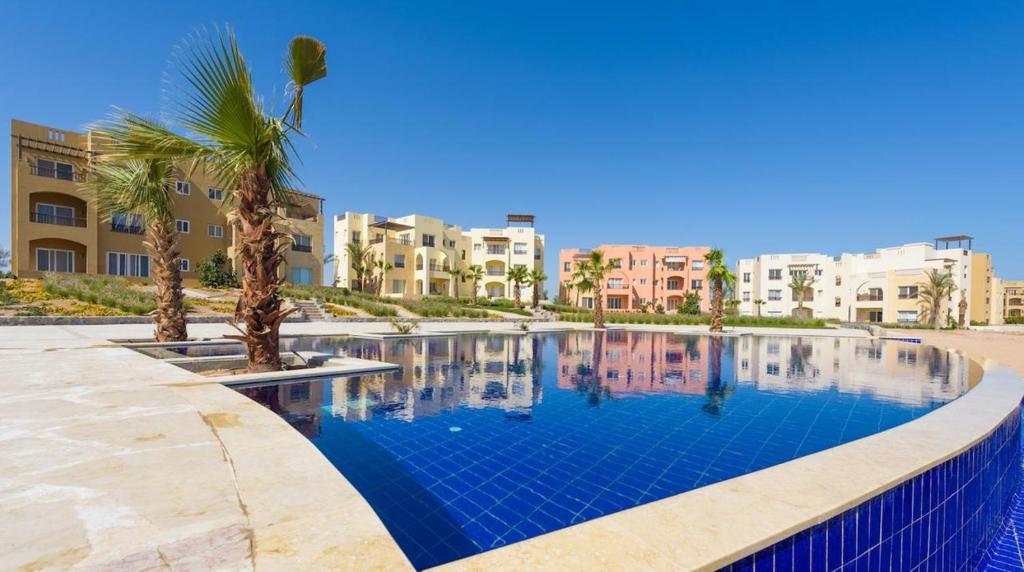 een zwembad met palmbomen en gebouwen bij Waterside Apartments, El Gouna - 1Bd Ground Floor in Hurghada