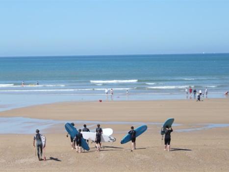 un grupo de personas de pie en una playa con tablas de surf en Albizia, en Saint-Julien-des-Landes