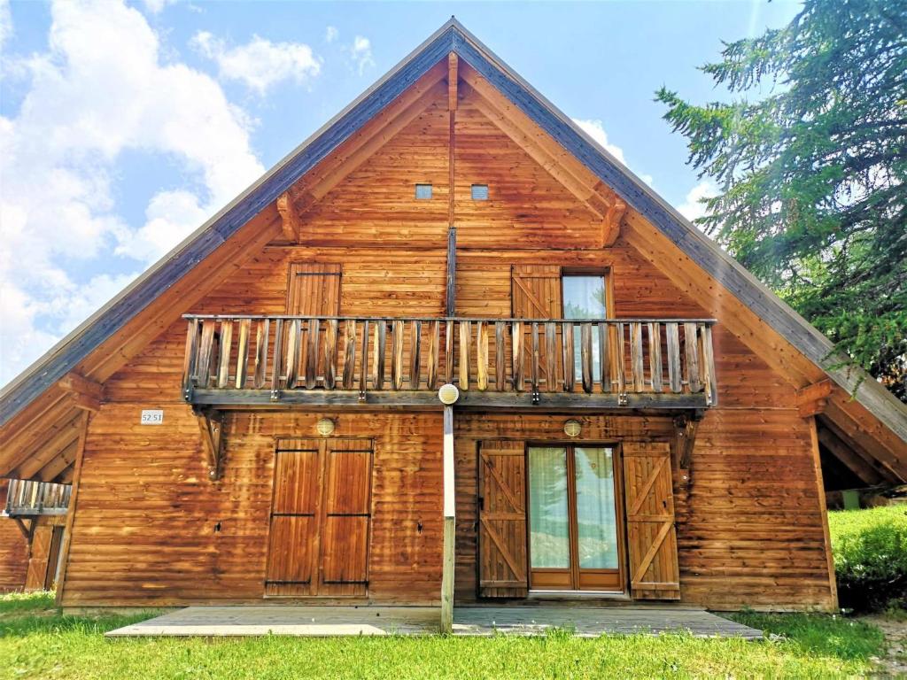 Cette maison en bois dispose d'un balcon. dans l'établissement Flocons du Soleil by Actisource, à La Joue du Loup