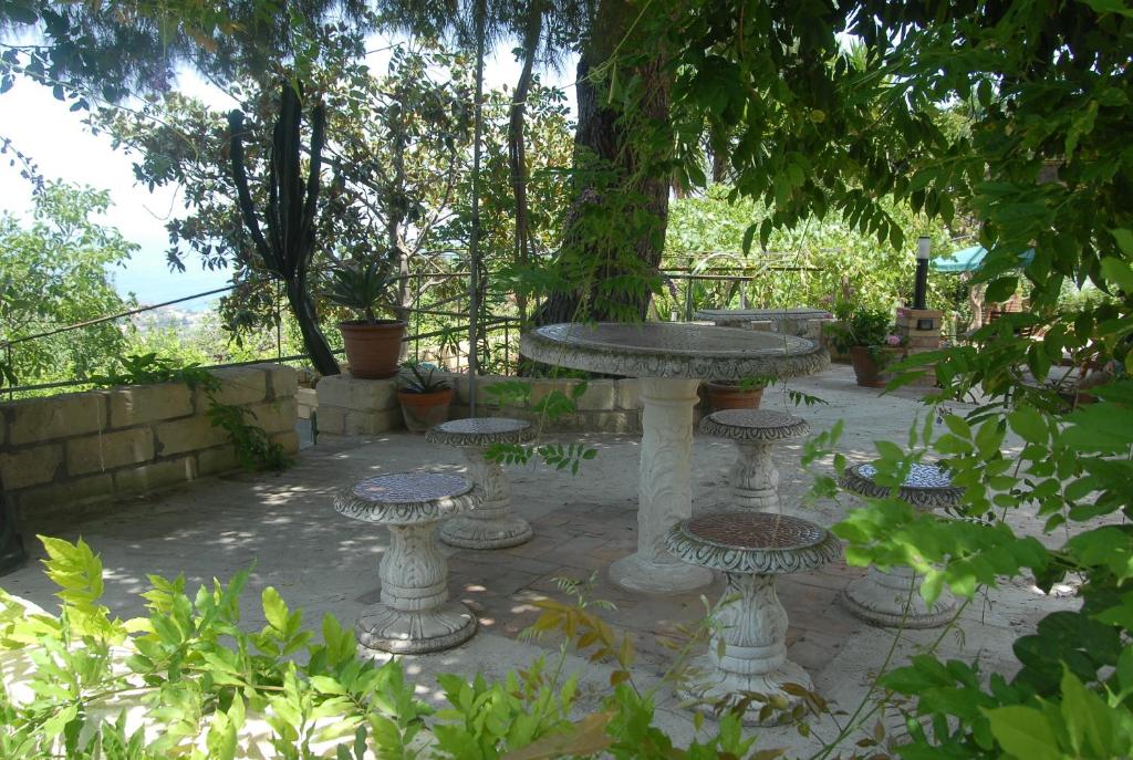 una mesa de piedra y sillas en un jardín en B&B Villa zia Febronia, en Patti