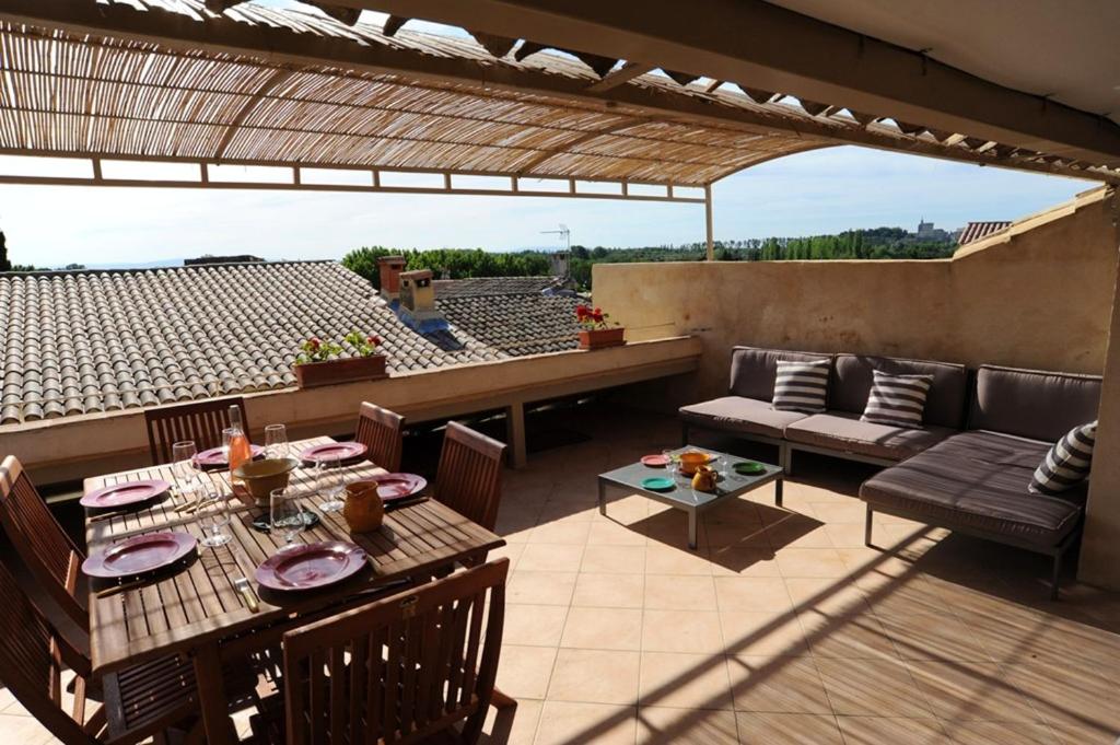 un patio avec une table et des chaises sur un toit dans l'établissement Maison confortable à Villeneuve-lès-Avignon, plancha incluse, à Villeneuve-lès-Avignon