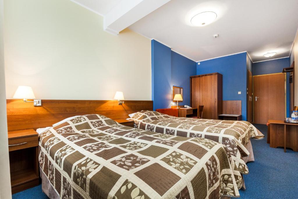 two beds in a hotel room with blue walls at Hotel Olivia in Gdańsk