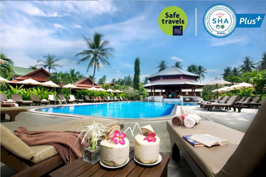 a pool at a resort with tables and chairs at Smile House - Fisherman Village in Bophut