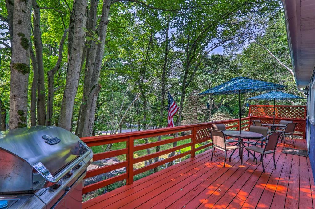 a wooden deck with chairs and a table and umbrella at Updated Blakeslee Cottage with Fire Pit and Deck! in Blakeslee
