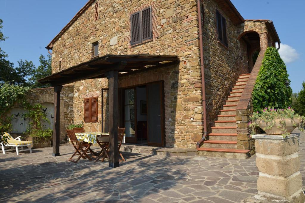 un edificio de ladrillo con un patio con mesa y sillas en Poggio Ferrone, en Suvereto