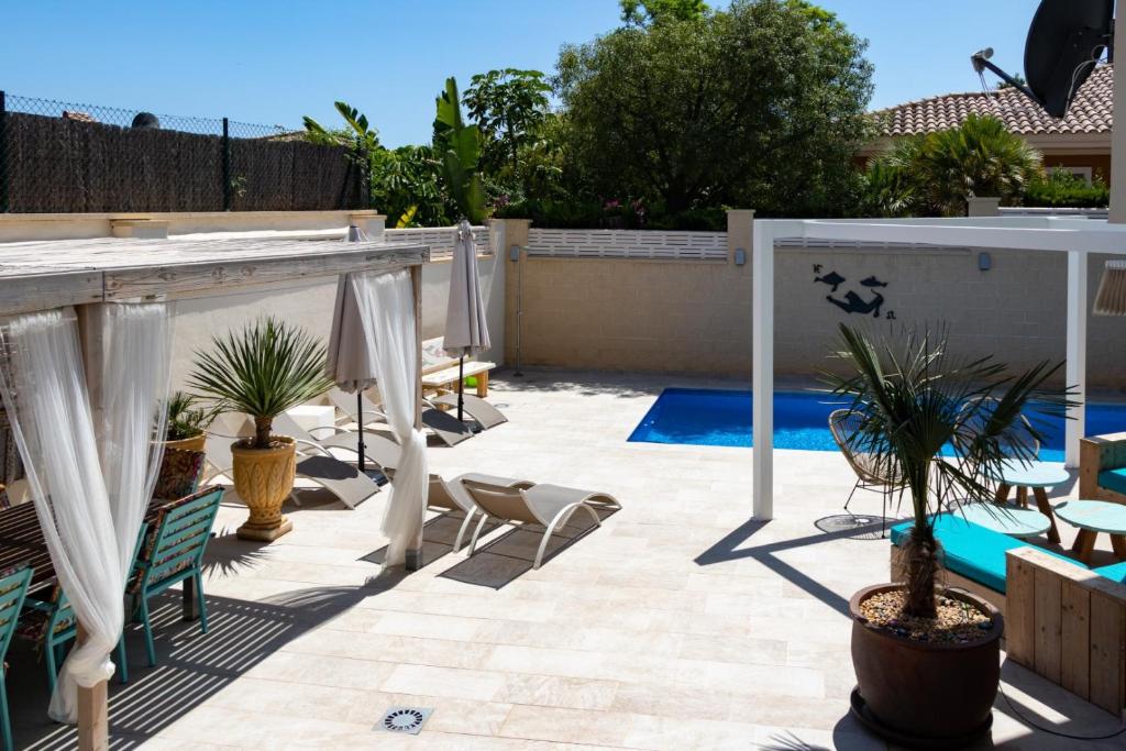 eine Terrasse mit Stühlen und Sonnenschirmen neben einem Pool in der Unterkunft Casa Verde Guesthouse in Mutxamel