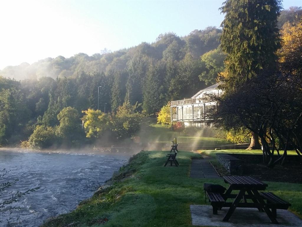 two benches sitting next to a river with a building at The Meetings B&B in Avoca