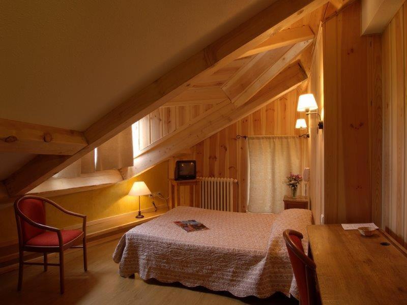 a bedroom with a bed and a table in a room at Hôtel Picheyre in Formiguères