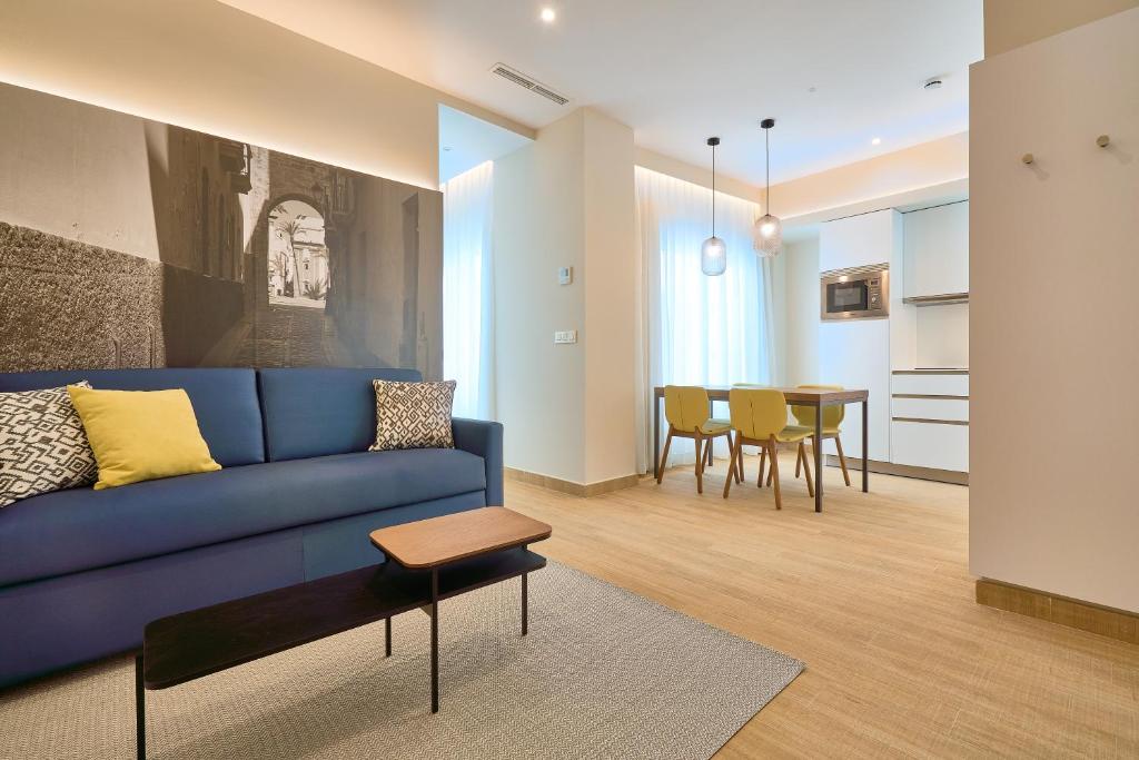 a living room with a blue couch and a table at Tandem Pópulo in Cádiz