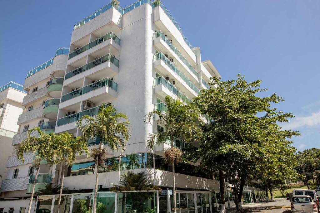 a tall white building with palm trees in front of it at Angra Beach Hotel in Angra dos Reis