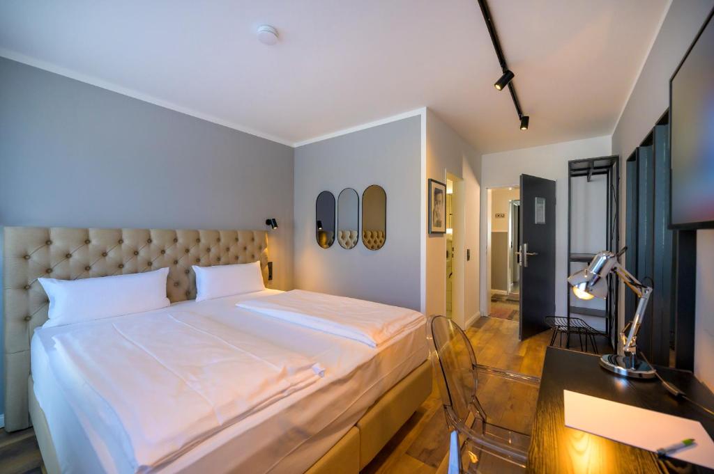 Nikii City Hotel في ليفركوزن: غرفة نوم بسرير كبير مع مكتب وكرسي