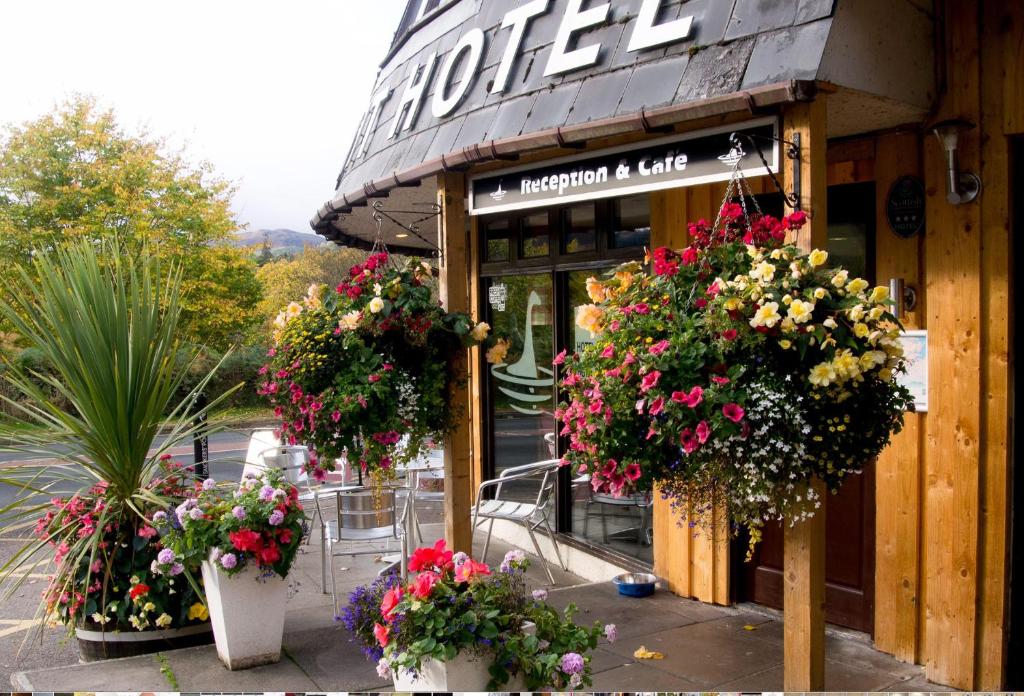 a store with flower baskets on the front of it at Loch Ness Drumnadrochit Hotel in Drumnadrochit