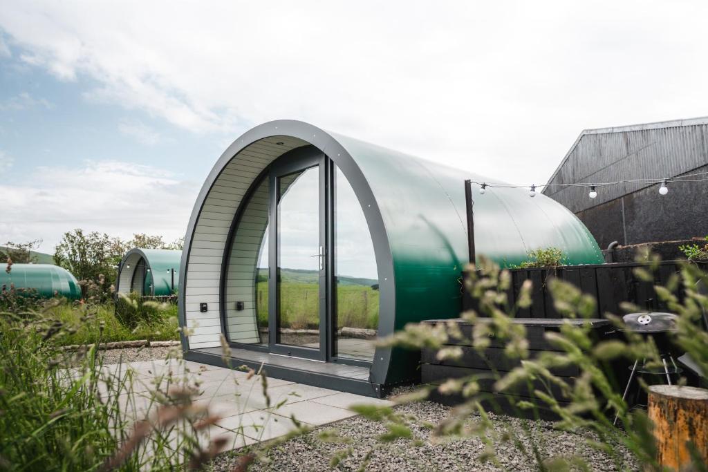 a circular building with a large window in a garden at Black Knowe, Luxury Glamping Pods, Ballycastle in Ballycastle