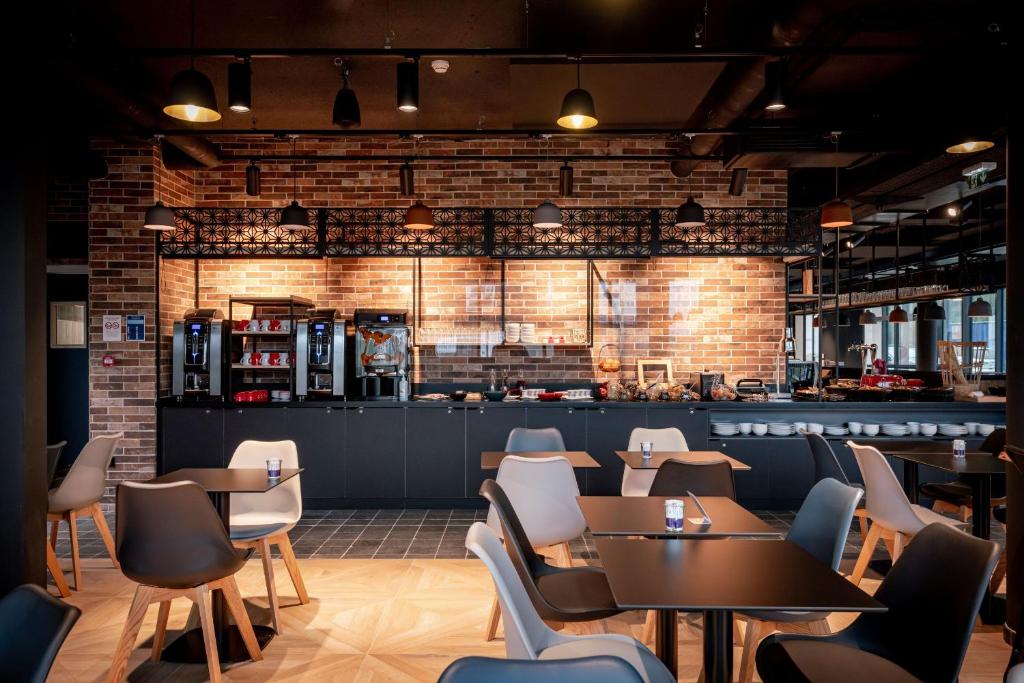 un restaurant avec des tables et des chaises et un mur de briques dans l'établissement ibis Styles Valenciennes Petite Foret, à Petite-Forêt