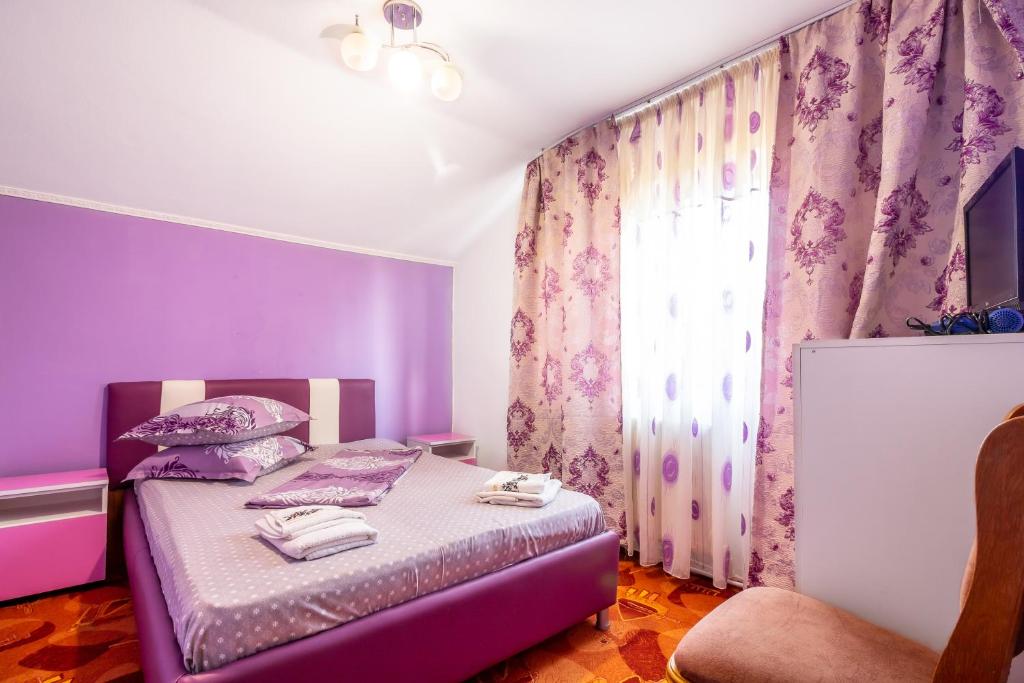 a purple bedroom with a bed and a window at Pensiunea Mariana in Baia de Fier