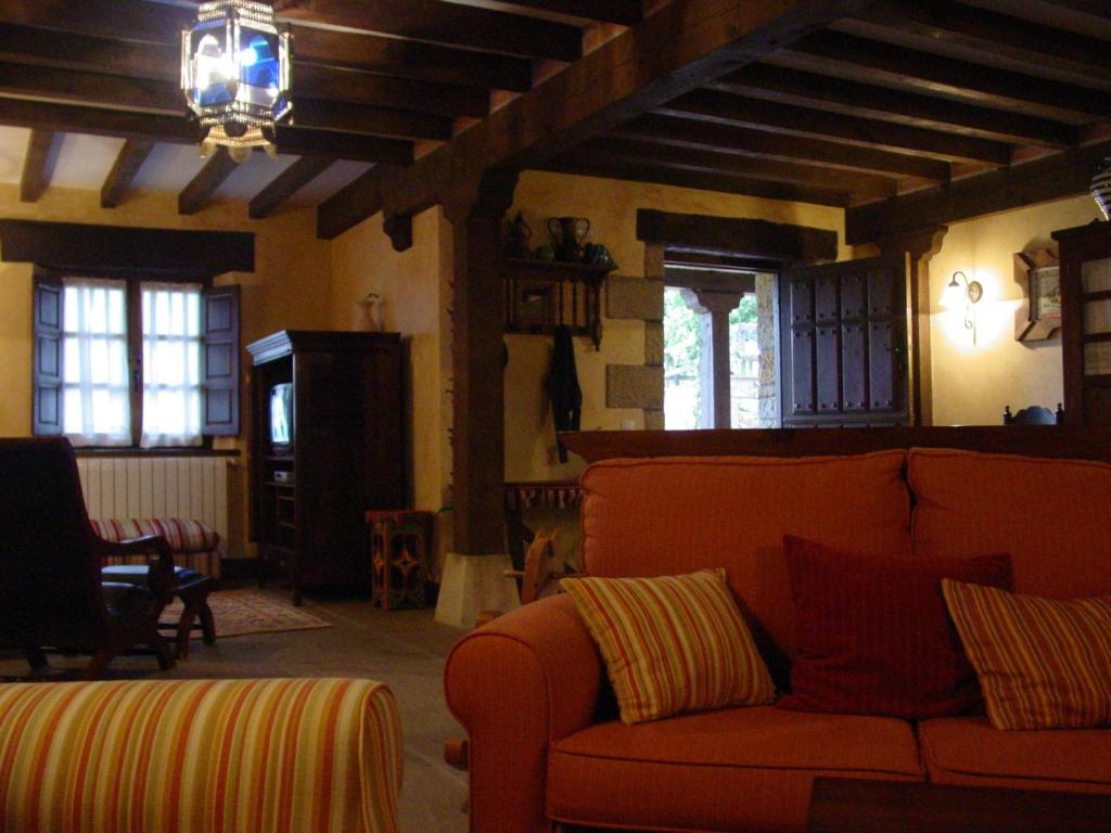 a living room with an orange couch in a room at Posada Rural Valoria in Valoria