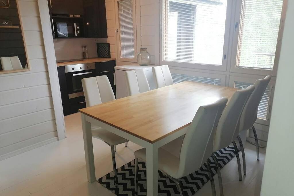 - une cuisine avec une table en bois et des chaises blanches dans l'établissement High Rise Cottage, à Muurame